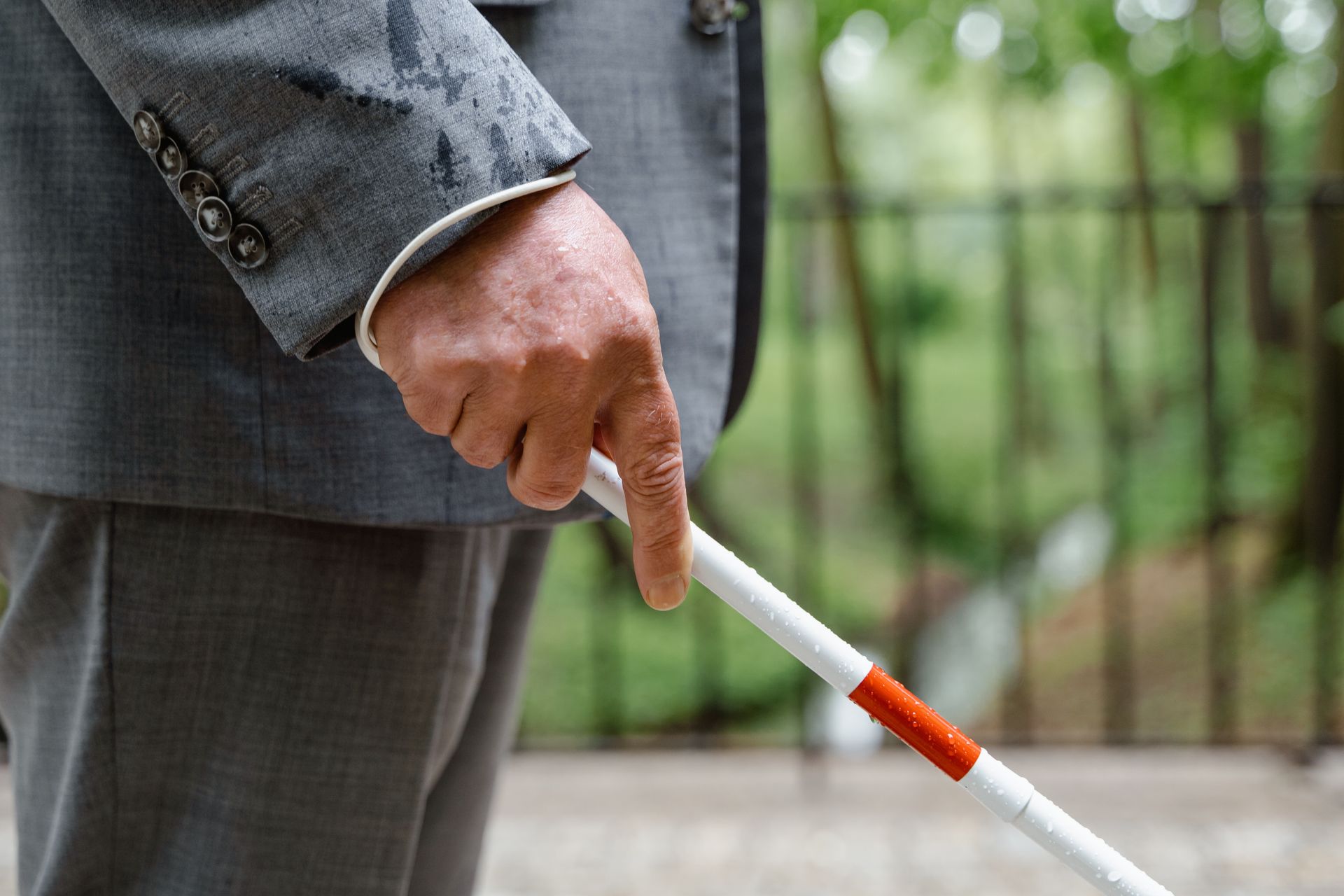 White middle aged man in gray suit holding a walking stick, stock photo