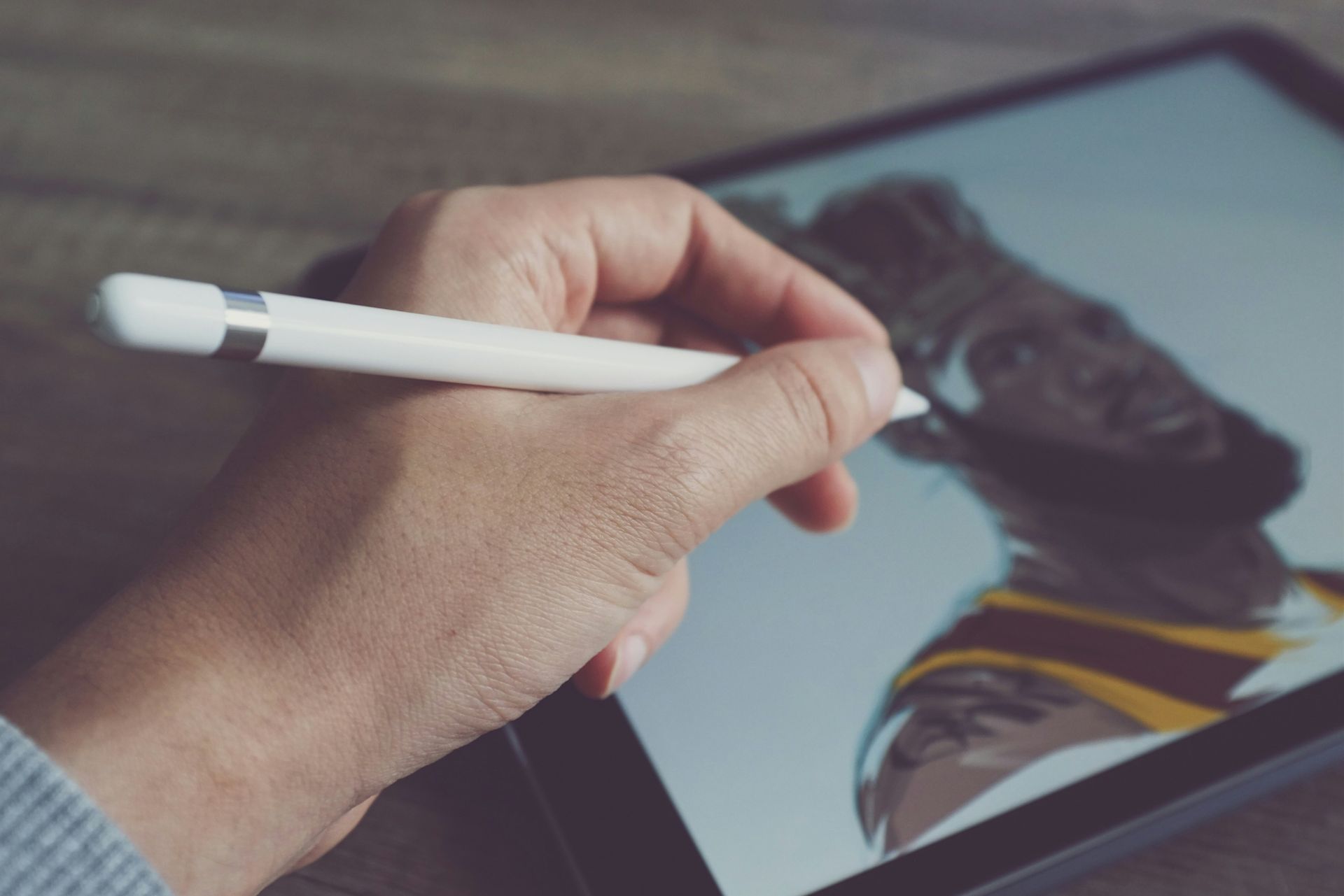 Close up of a white man's hand, drawing a picture on an iPad with an Apple Pencil.